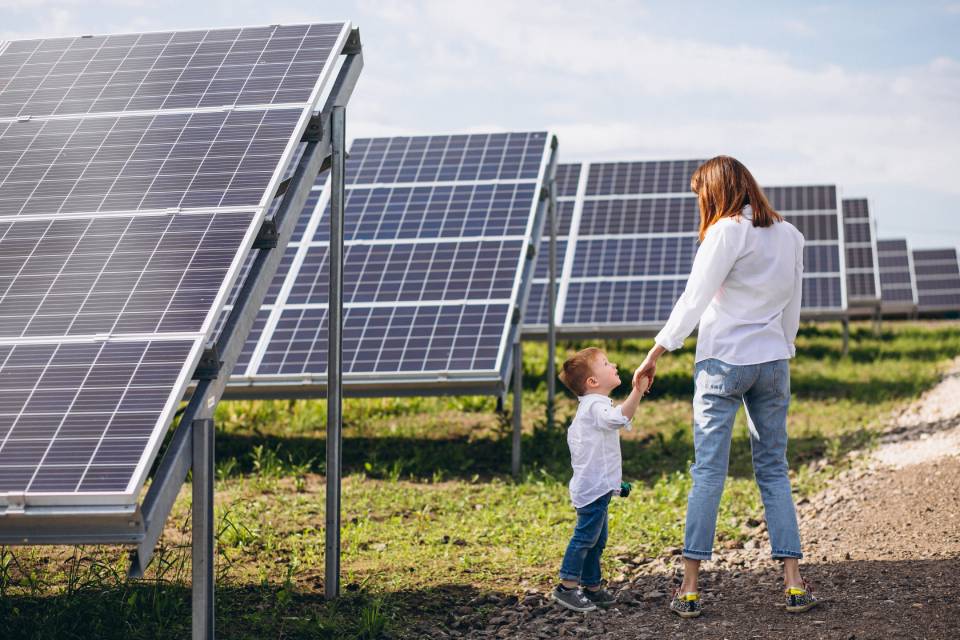 a girl standing with her child in a solar panel field